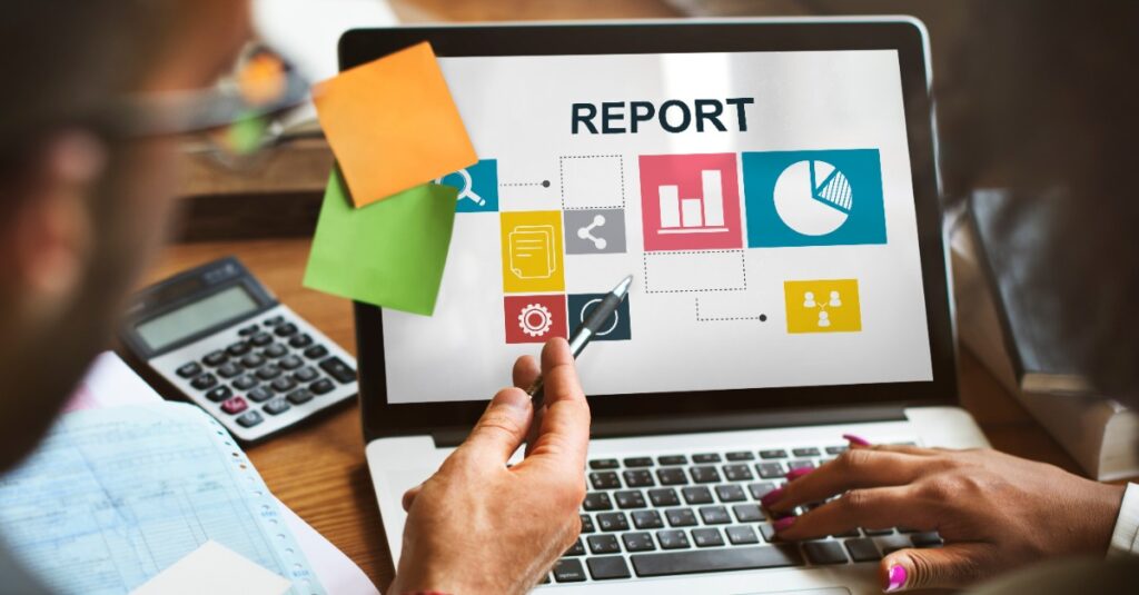 Business Owners Viewing Self Storage Reporting Software Report On Computer Desk